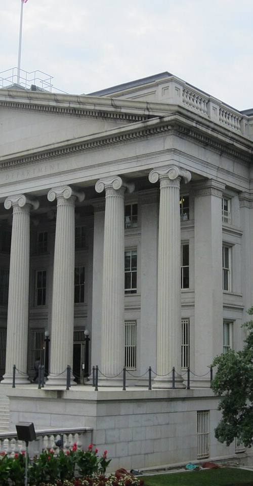 Fachada principal del edificio del Departamento del Tesoro de EE. UU. en Washington D.C., con columnas jónicas y el rótulo "THE TREASURY DEPARTMENT" tallado en el friso