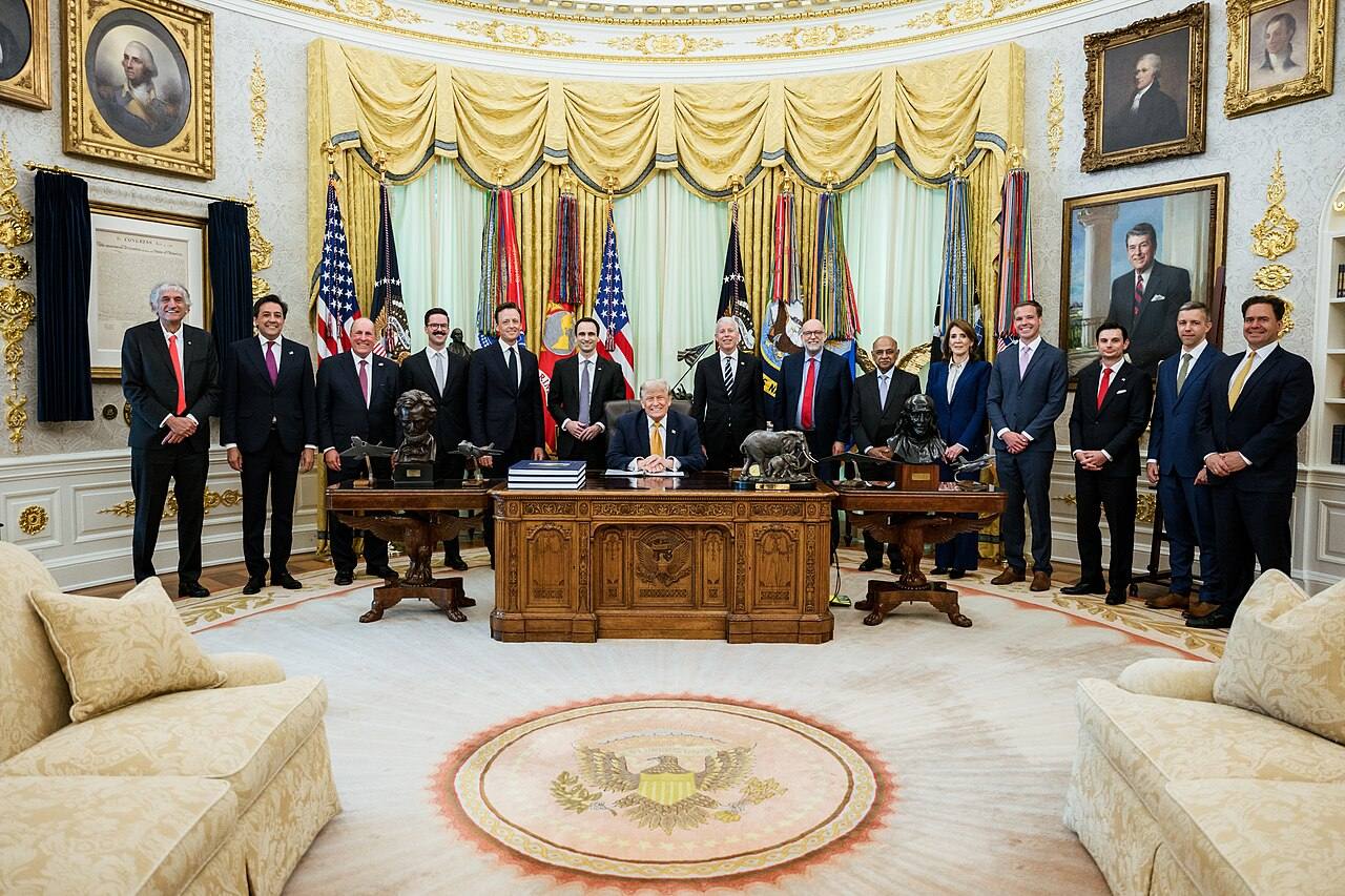 Donald Trump sentado al Resolute Desk del Despacho Oval, rodeado de miembros del Gabinete y asesores, momentos antes de firmar la orden ejecutiva sobre computación cuántica el 22 de junio de 2026
