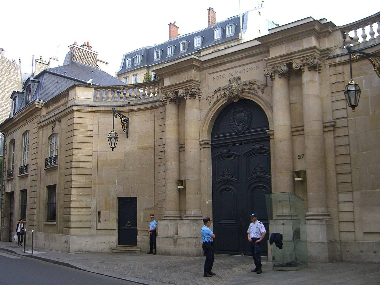 Verja de entrada del Hôtel de Matignon en París, con "HOTEL DE MATIGNON" tallado en piedra sobre la puerta y dos gendarmes franceses de guardia en el acceso