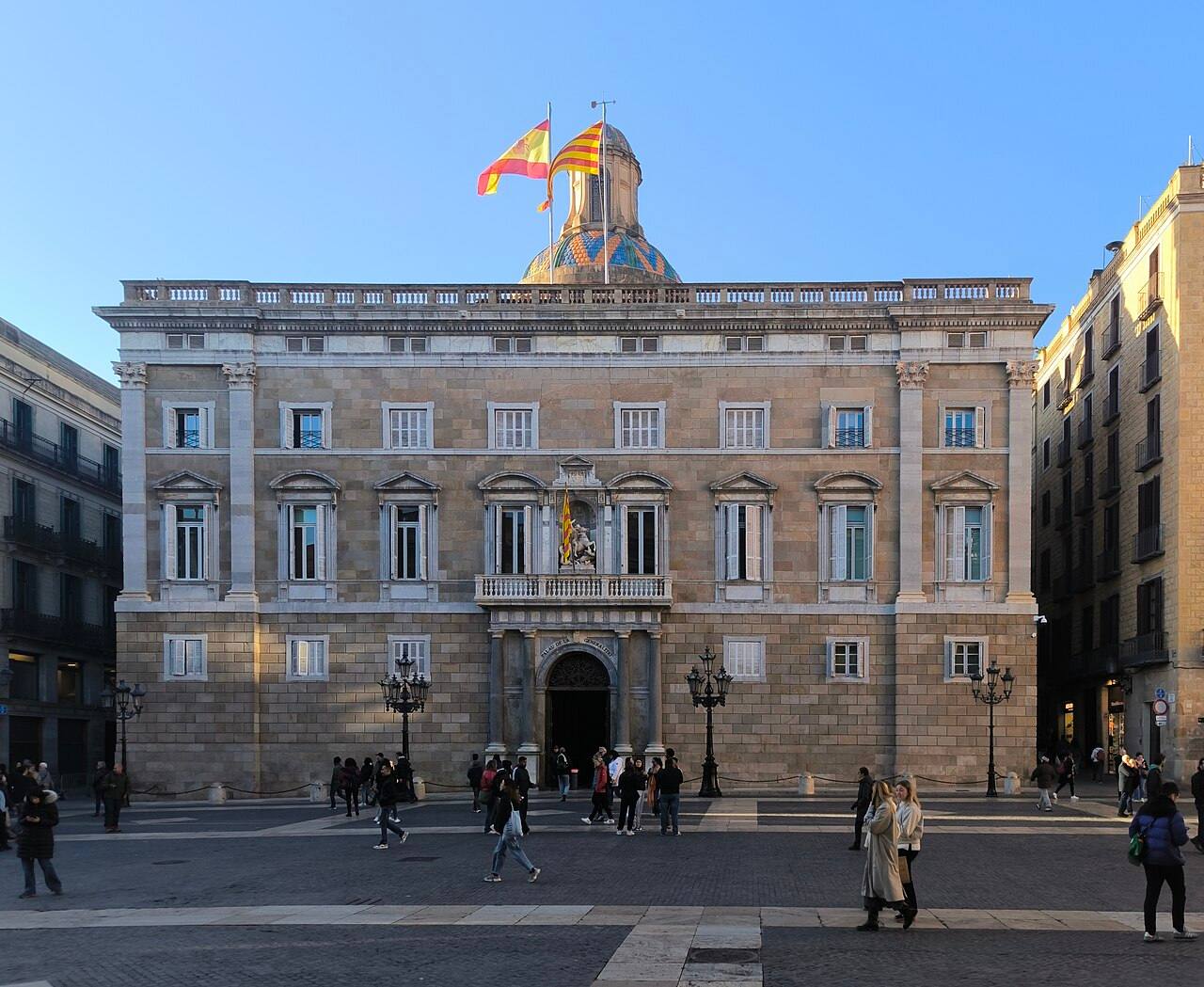 Fachada principal del Palau de la Generalitat de Catalunya, con las banderas catalana y española ondeando sobre la cúpula, en la plaça de Sant Jaume de Barcelona