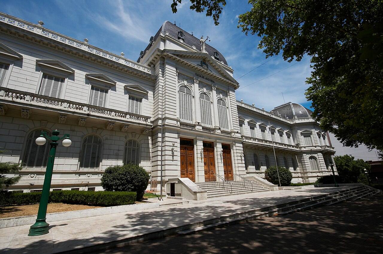 Fachada principal del Palacio de Justicia de La Plata, con la inscripción tallada "Casa de Justicia", columnas clásicas y la estatua de la Justicia sobre la cúpula; el edificio es la sede de la Suprema Corte de Justicia de la Provincia de Buenos Aires.