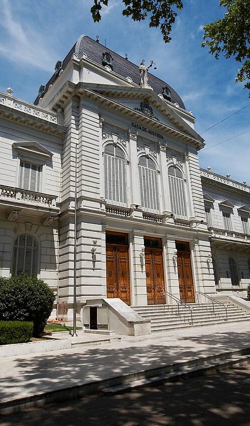 Fachada principal del Palacio de Justicia de La Plata, con la inscripción tallada "Casa de Justicia", columnas clásicas y la estatua de la Justicia sobre la cúpula; el edificio es la sede de la Suprema Corte de Justicia de la Provincia de Buenos Aires.