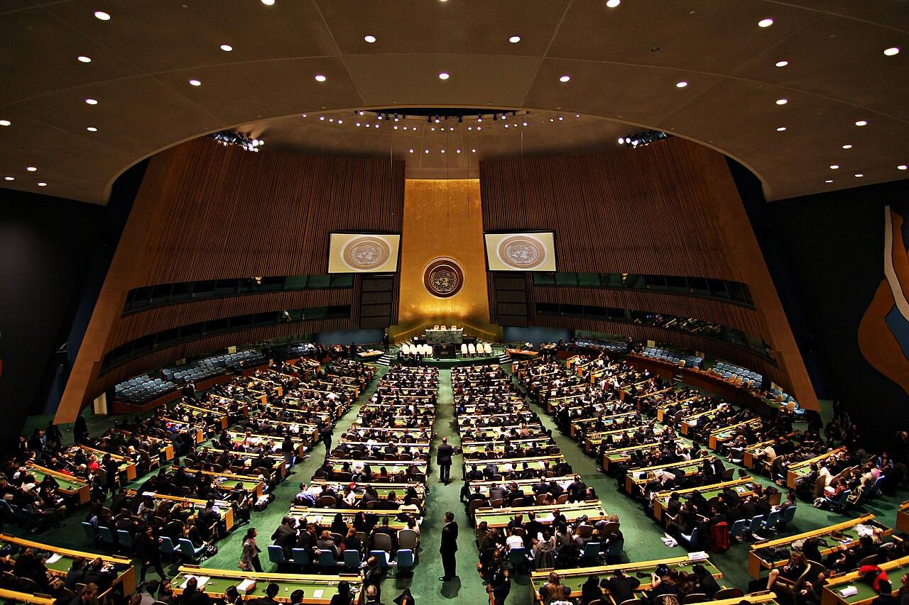 Delegados sentados en la sala de la Asamblea General de la ONU en Nueva York durante una sesión plenaria, con el emblema de la organización iluminado al fondo