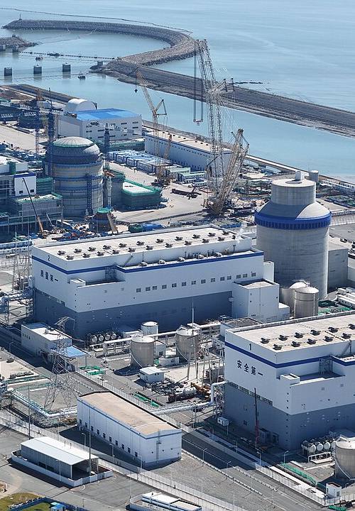 Vista aérea de la central nuclear de Haiyang, en Shandong (China), con los reactores 3 y 4 en construcción: cúpulas de contención de hormigón sin terminar rodeadas de grúas torre junto a la costa