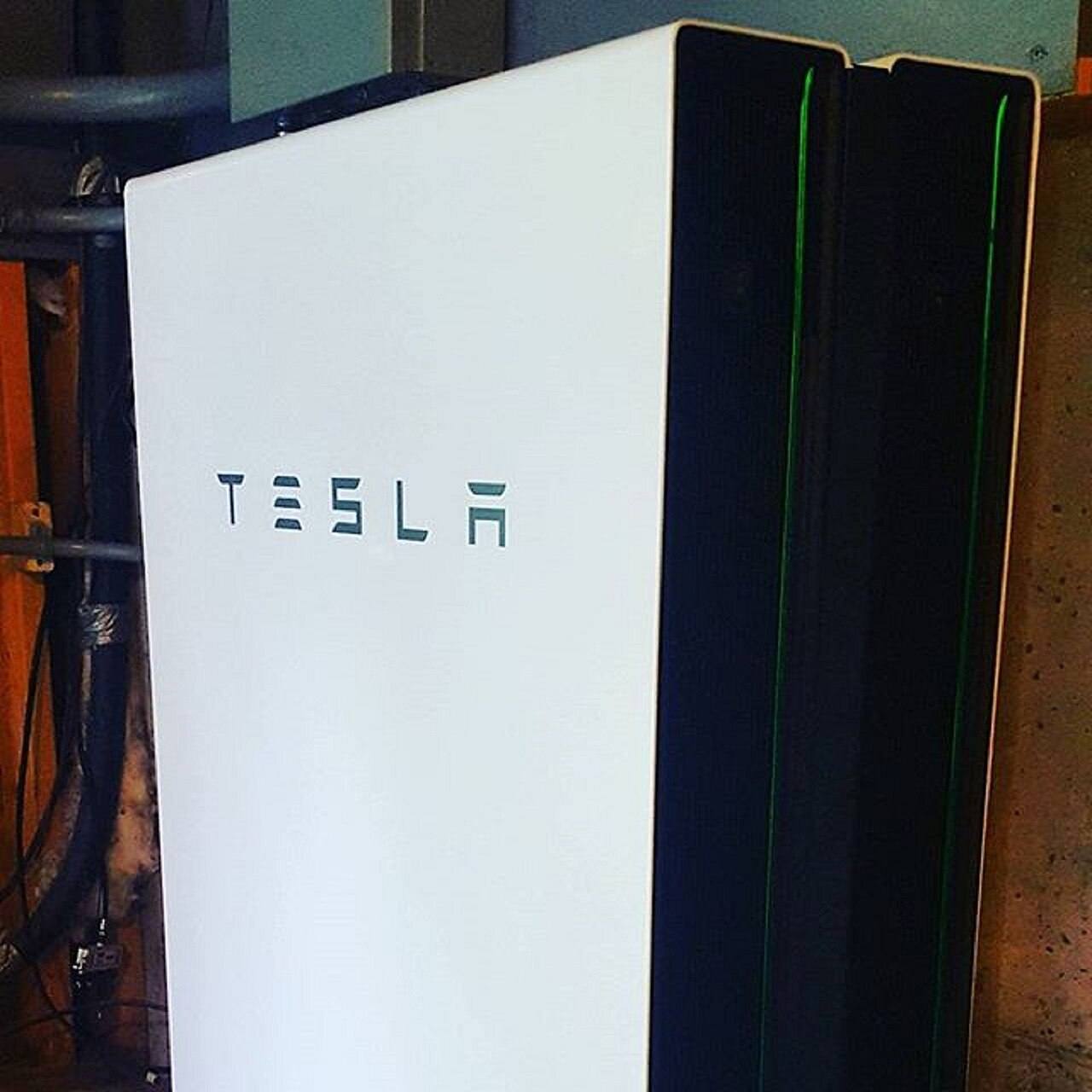 Batería doméstica Tesla Powerwall instalada en la pared de una vivienda en el estado de Nueva York, con tuberías y cableado visibles alrededor