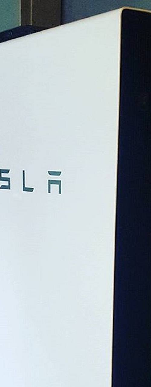 Batería doméstica Tesla Powerwall instalada en la pared de una vivienda en el estado de Nueva York, con tuberías y cableado visibles alrededor