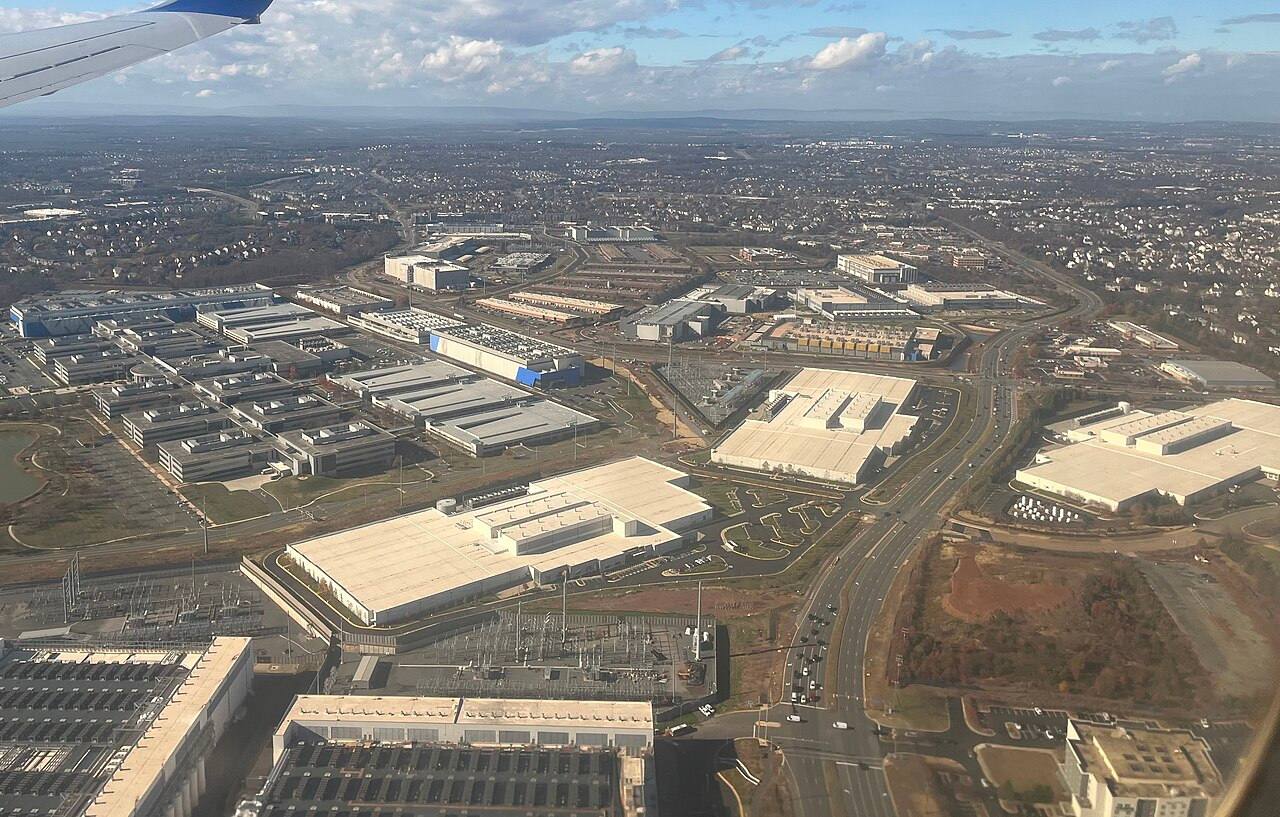 Vista aérea desde un avión de un enorme complejo de naves de centros de datos de techo blanco, con una subestación eléctrica junto a ellas, en el condado de Loudoun, cerca de Ashburn, Virginia