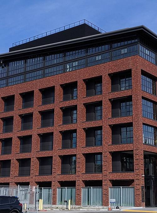 Edificio de ladrillo de la sede de Stripe en San Francisco, con el rótulo "stripe" sobre la entrada y palmeras junto a la puerta principal