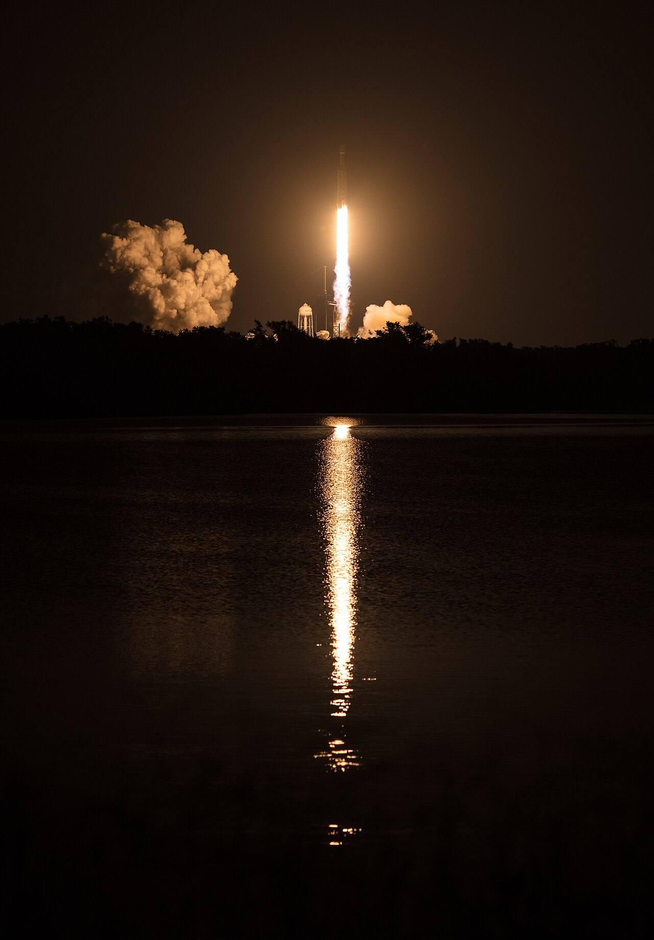 El despegue nocturno de un cohete Falcon Heavy reflejado sobre el agua