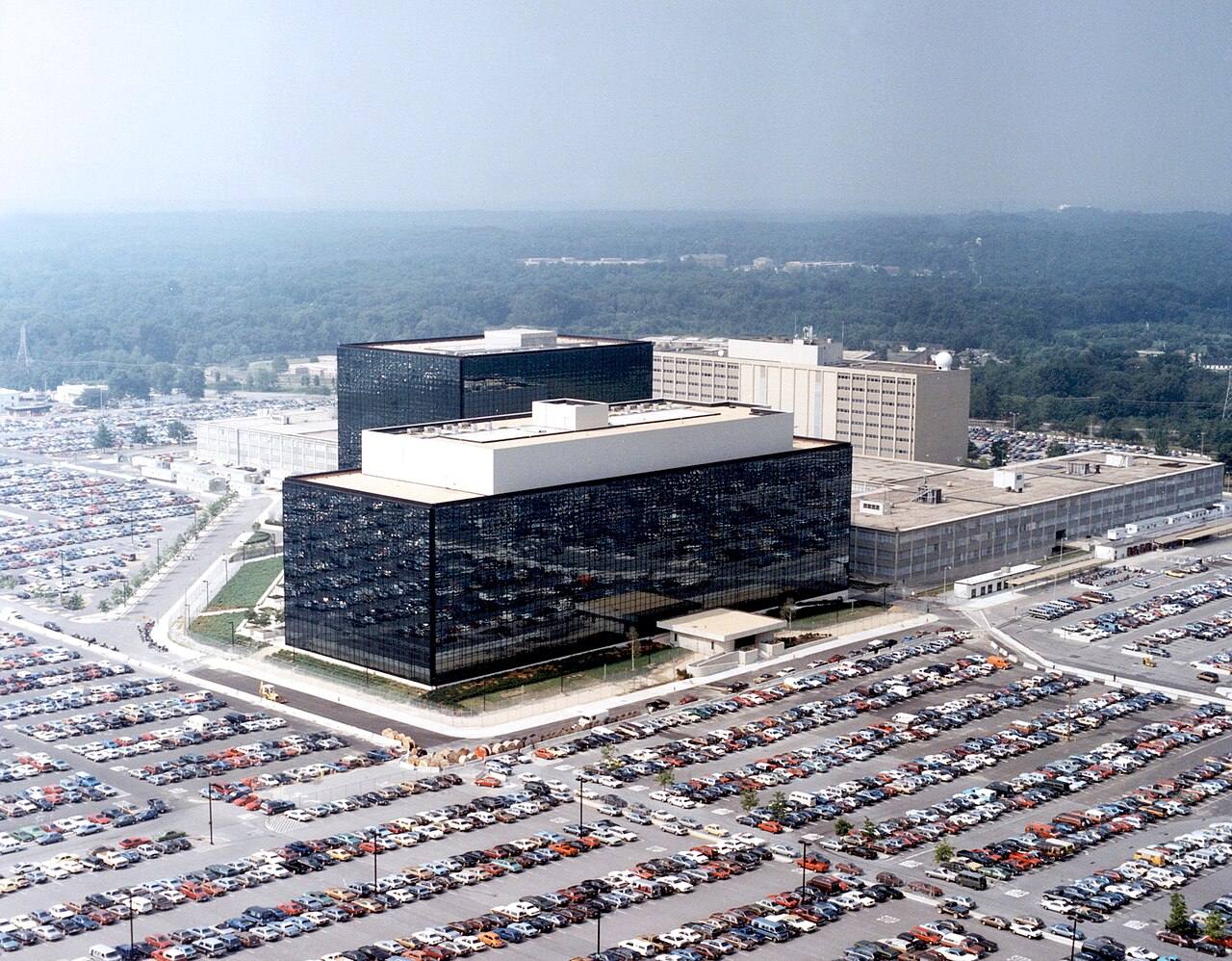 Vista aérea de la sede de la Agencia de Seguridad Nacional (NSA) de EE. UU. en Fort Meade, Maryland: el edificio de fachada de cristal oscuro rodeado de amplios aparcamientos