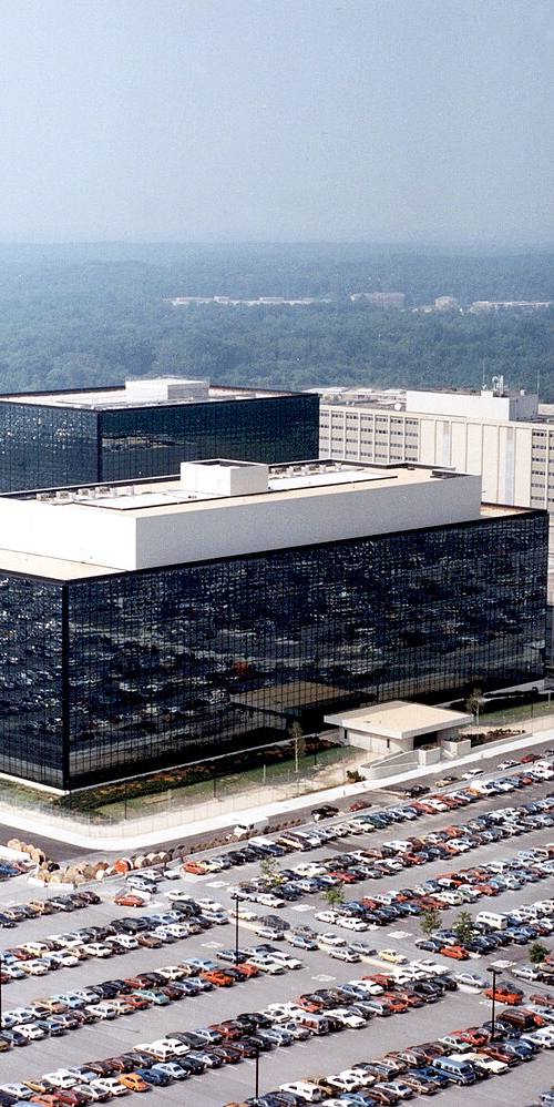 Vista aérea de la sede de la Agencia de Seguridad Nacional (NSA) de EE. UU. en Fort Meade, Maryland: el edificio de fachada de cristal oscuro rodeado de amplios aparcamientos