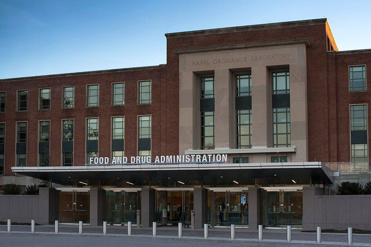 Entrada principal del campus de la FDA en White Oak, Maryland, con el rótulo "Food and Drug Administration" sobre el acceso acristalado, fotografiada al atardecer.