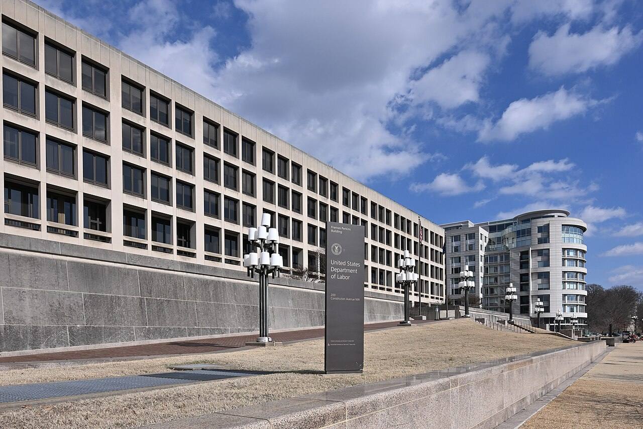 Cartel institucional de la sede del Departamento de Trabajo de Estados Unidos en Washington D. C., con el edificio Frances Perkins al fondo
